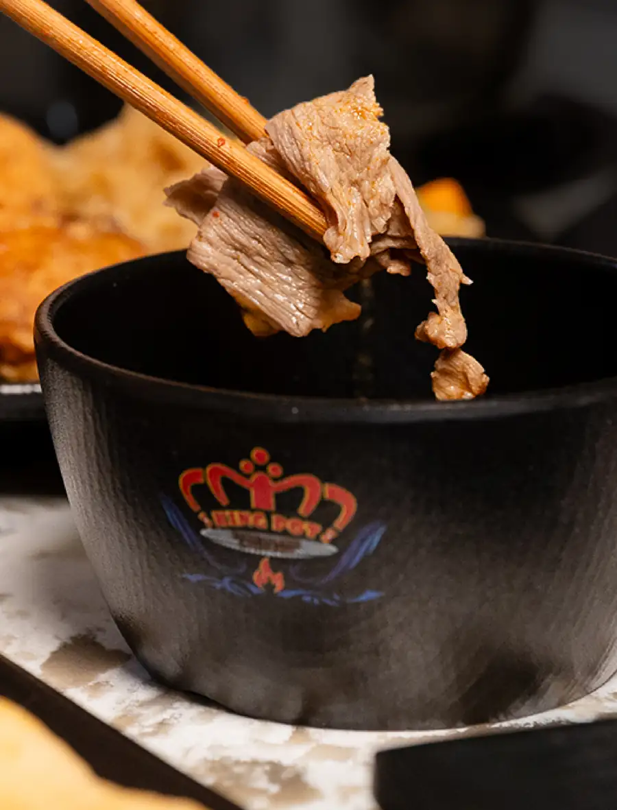 Dipping beef into a King Pot sauce bowl