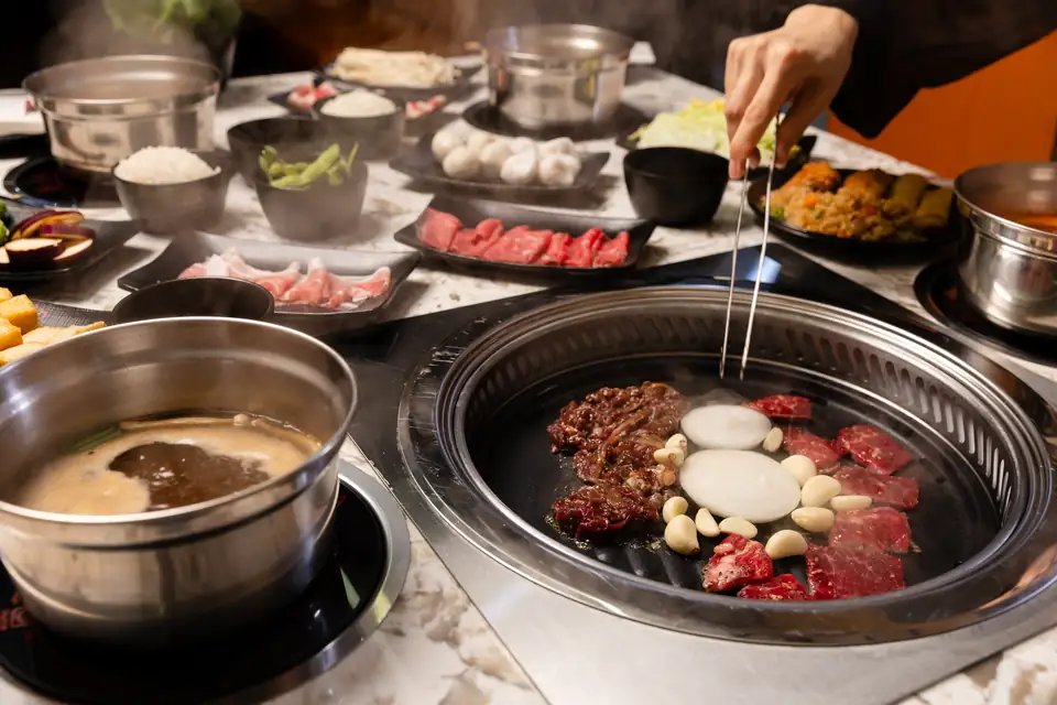 Hotpots and a tabletop grill surrounded by plates